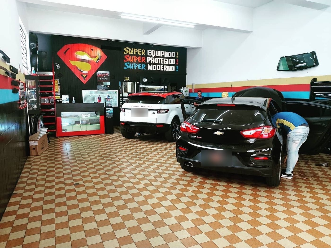 Loja por dentro, piso xadrez e carros em serviço