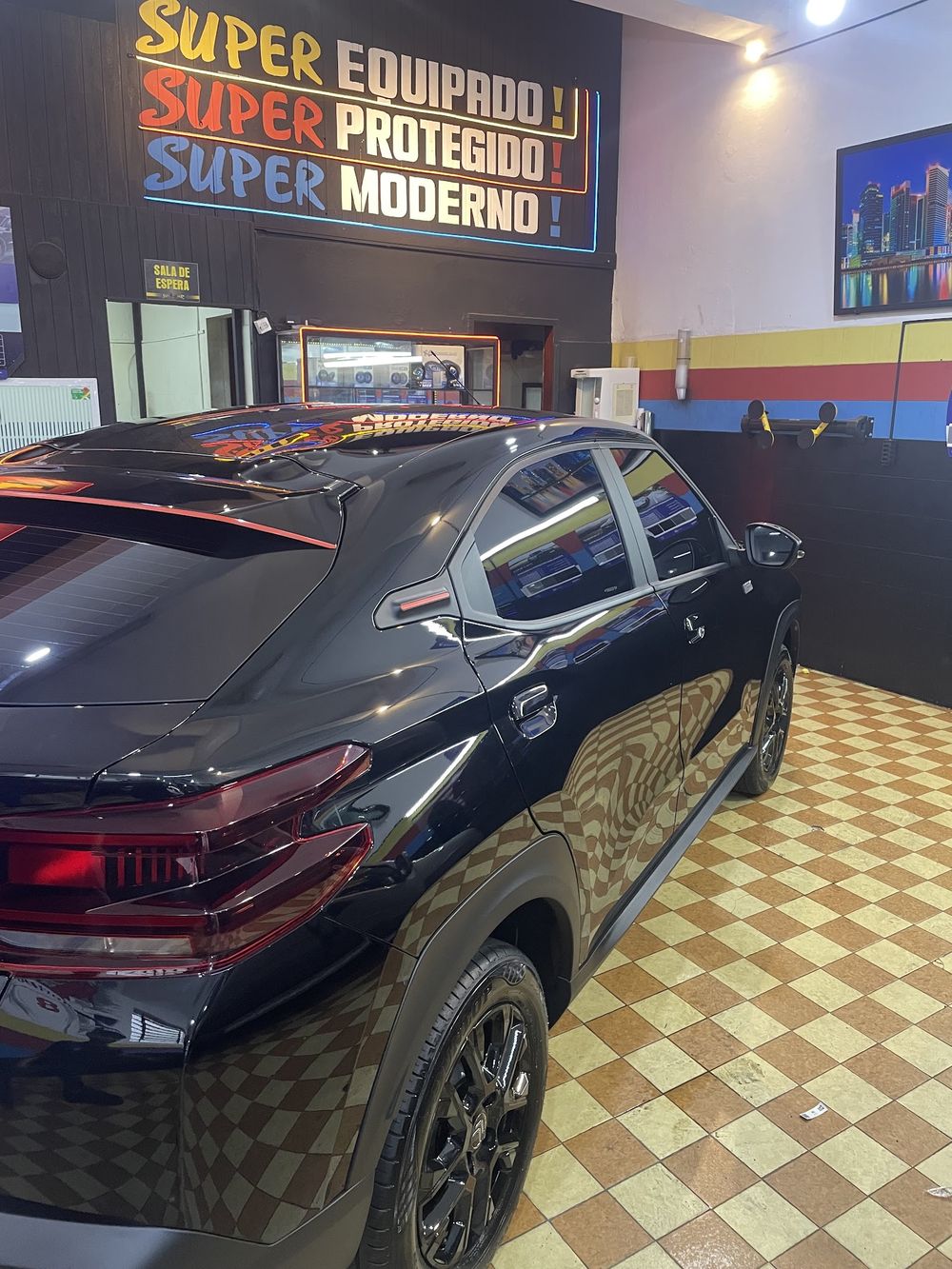 Carro preto na frente do mural Super equipado, Super protegido, Super moderno